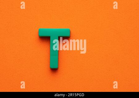 Alphabet letter L - Green plastic piece on orange foamy background ...