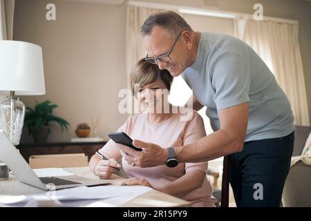 Can I just stop you for a second. a mature husband and wife together using a smartphone. Stock Photo