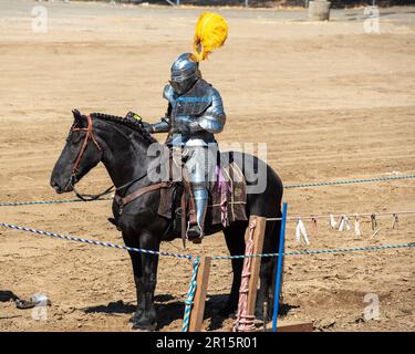 Folsom, CA, September 24, 2022. Unidentified young male at the Folsom Renaissance Faire dressed as a knight ridig a black horse in the arena Stock Photo