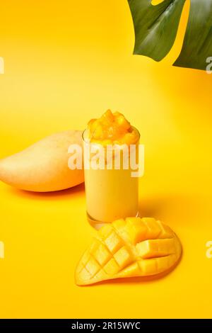 Juicy Mango Smoothie with fresh mango slices on yellow background.Thai Sweet mango drinks.Summer Drinks Concept.Yellow Drinks.Fresh fruit juice Stock Photo