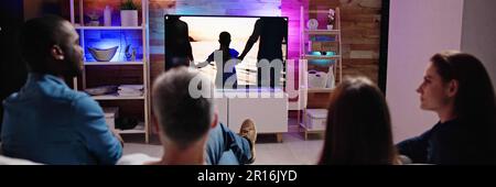 Couples Watching TV At Night. Television Screen Stock Photo