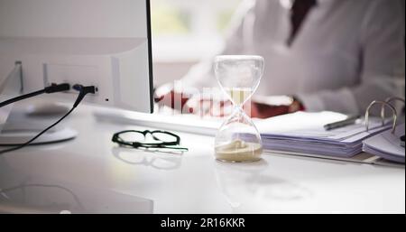 Late Invoice And Billing Deadline With Hourglass At Desk Stock Photo