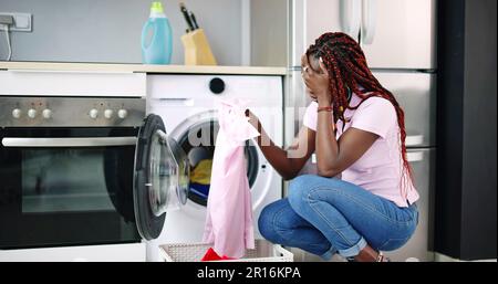 Young Woman Crouching With Cleaned Clothes Near The Electronic Washer Stock Photo