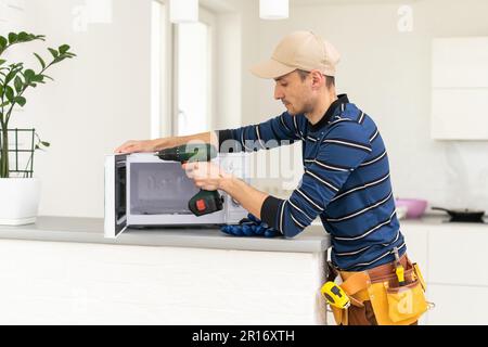 man repairing microwave. a worker repairs a microwave oven. Stock Photo