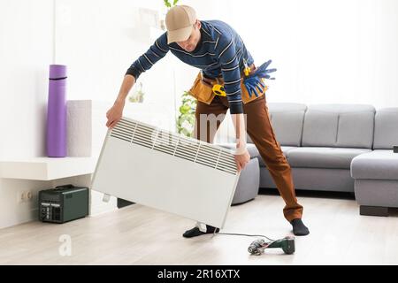 the master repairs the electric heater Stock Photo