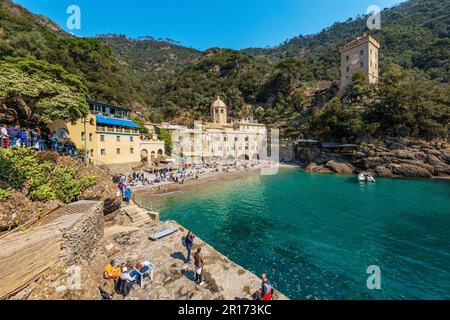 Ancient San Fruttuoso Abbey, X-XI century and the ancient Andrea Doria tower, beach crowded with tourists near Portofino and Camogli, Genoa, Liguria, Stock Photo