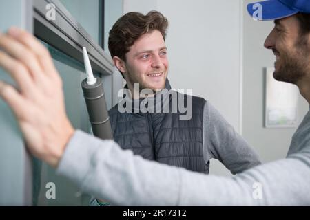 apprentice and workers using silicone pistol Stock Photo