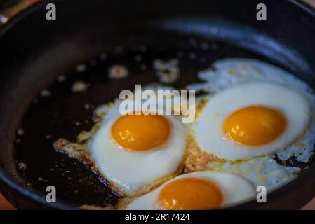 three eggs fried in frying pan scrambled eggs. Healthy food, nutritious delicious breakfast hot oil Stock Photo