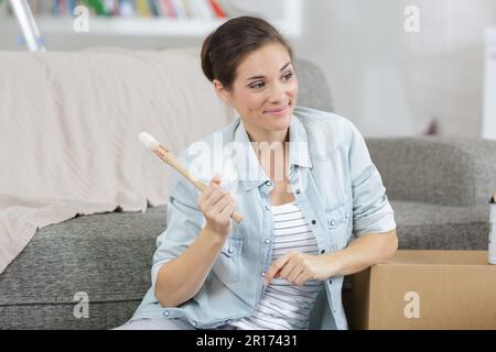 beautiful female sitting on floor with sampler and paint brush Stock Photo
