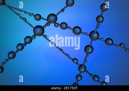 A number of water droplets clinging to a fishing line against a blue background Stock Photo