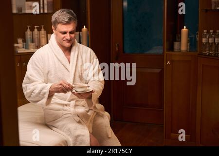 Spa client relaxing with healthy beverage before treatment procedure Stock Photo