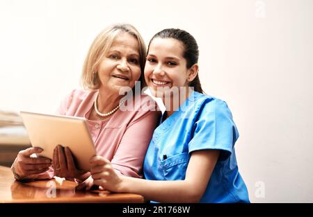 Connected in so many ways. a female nurse and a senior woman using a digital tablet together. Stock Photo