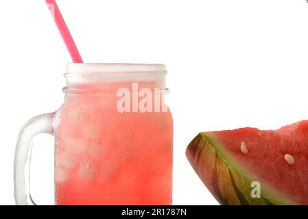 Detail of jar with cold watermelon drink with ice and fruit on the side and white isolated background. Front view. Horizontal composition. Stock Photo