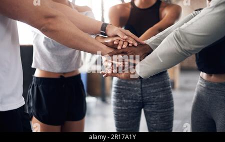 Time to power up. a group of young people joining their hands together in solidarity at a gym. Stock Photo