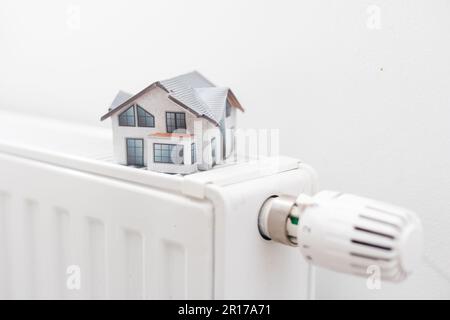 Model of house on white radiator. Stock Photo
