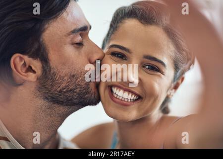 Were happy together. Portrait of a happy young couple posing for a selfie on their couch at home. Stock Photo
