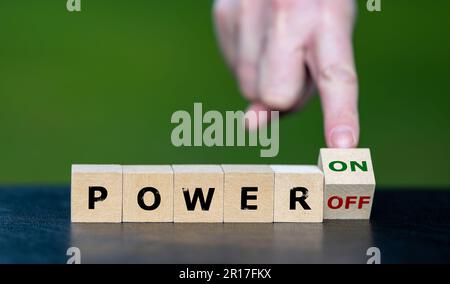 Hand turns wooden cube and changes the expression 'power off' to 'power on'. Stock Photo