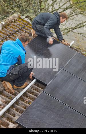 Photovoltaic solar panels being fitted to a residental roof in England, Great Britain. Stock Photo