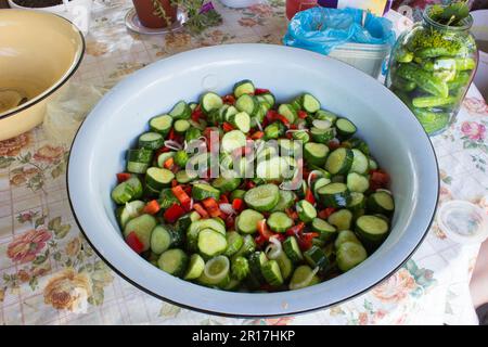 Sliced cucumber and red pepper for winter conservation on the table Stock Photo