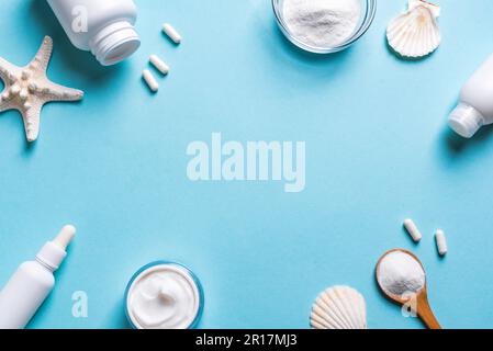 Collagen powder and collagen beauty products - capsules (pills), face cream, serum on blue background, copy space.  Fish based collagen food supplemen Stock Photo