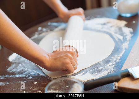 Woman rolling dough with rolling pin in a home kitchen Stock Photo