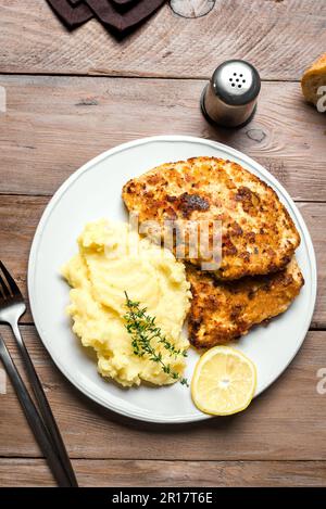 German schnitzel with fresh mashed potatoes on wooden table. Homemade breaded pork meat chop. Wiener Schnitzel. Stock Photo
