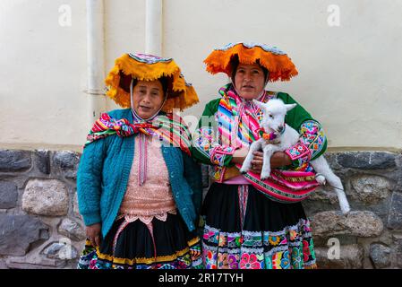 Two women in traditional clothing and a goat posing for tourists Stock Photo