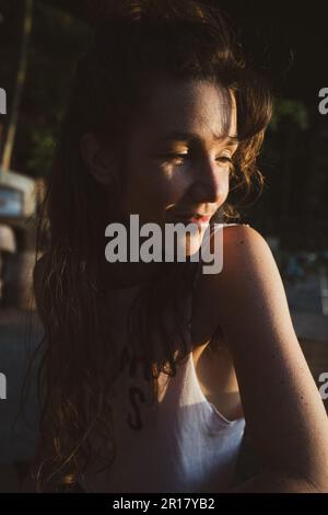 sunlit portrait of natural woman smiling in golden hour sun Stock Photo