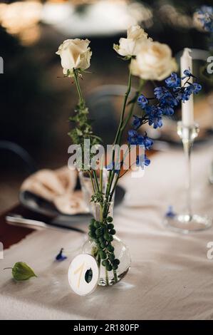 A wedding table set decorated with a selection of tall glass vases containing white flowers. Stock Photo