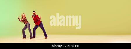 Artistic, beautiful, emotional man and woman in stylish retro clothes dancing against gradient green yellow background Stock Photo