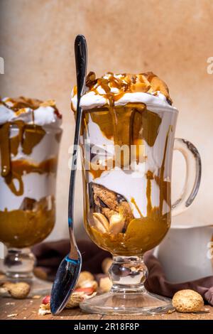 Peanut butter trifle, parfait layered dessert in glass with whipped cream, peanut cookies, toffee, nuts butter and caramel sauce Stock Photo