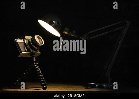A photo of an old film metallic camera looking on a warm bulb Stock Photo