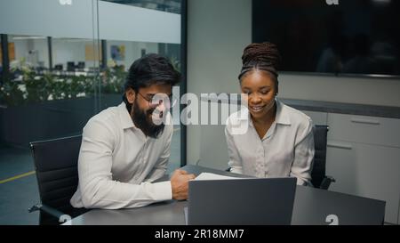 Business partners happy multiracial diverse company coworkers colleagues in office meeting Indian man and African woman online working together work Stock Photo