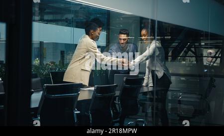Multi-ethnic diverse business team coworkers colleagues corporate partners workers win with laptop celebrating good online result success stack hands Stock Photo