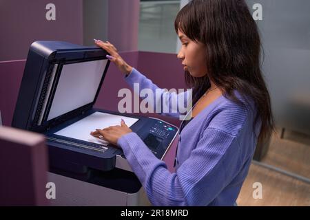 Serious woman worker using multifunction printer in office Stock Photo
