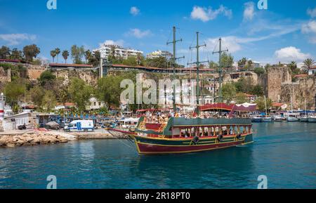 A tourist boat sails through the ancient harbour in Kaleici, the charming old town in Antalya, Turkey, on a sunny day. The boat is just one of many th Stock Photo