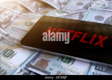 Netflix logo displayed on smartphone on top of pile of money. Stock Photo