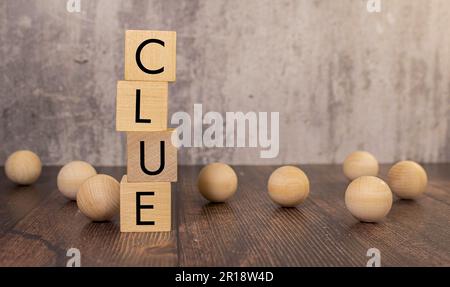 a pyramid of wooden cubes with the word CLUE and wooden balls around on a bright blue background, copy space on the right Stock Photo