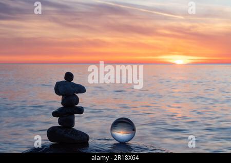 Stone pyramids and glass sphere on the dreamy Baltic Sea sand beach on Rügen to the spectacular orange sunset Stock Photo