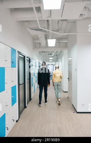 Colleagues walking along storage cells to office Stock Photo
