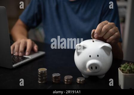 Man holding coin in white piggy bank, investment, finance, banking, savings and retirement concept Stock Photo