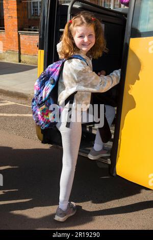 Year 4 Schoolgirl / girl / child / kid / student pupil aged 8 years boarding a coach school bus at the start of a school trip. England UK. (134) Stock Photo