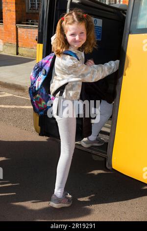 Year 4 Schoolgirl / girl / child / kid / student pupil aged 8 years boarding a coach school bus at the start of a school trip. England UK. (134) Stock Photo