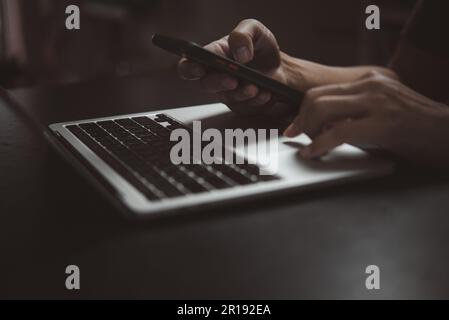 man using working searching information mobile smart phone and working on laptop compute. Stock Photo