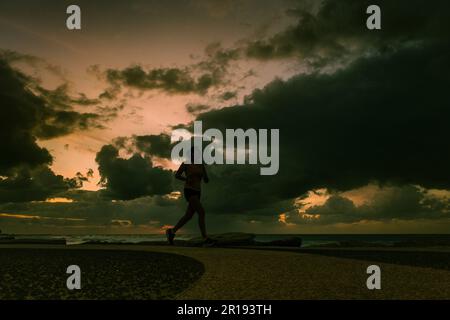 Sunset, female jogger running along the promenade in Tel Aviv Dec 2022 A storm has passed and there is a beautiful sunset Stock Photo