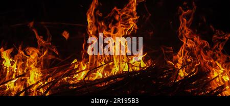 Fire flames with sparks on the night black background. Heat energy heap closely. Burning power filmed on high speed cinema camera Stock Photo