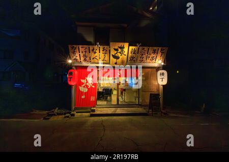 Higashikakogawa, Japan - May 5, 2023: Traditional wooden menu signs over bright lights at restaurant entrance Stock Photo