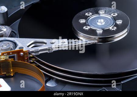 Internal components of a computer hard disk drive used for data storage. Metal disk platters, actuator head and orange ribbon cable. Stock Photo