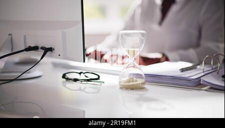 Late Invoice And Billing Deadline With Hourglass At Desk Stock Photo