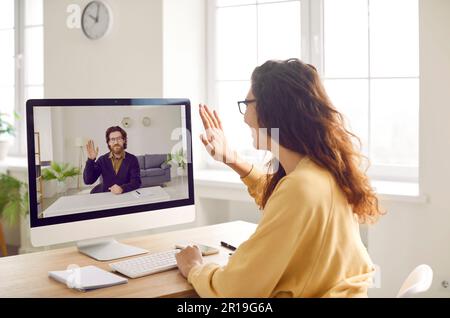 Happy smiling woman waving hand saying hello having online video call with colleague or a friend. Stock Photo